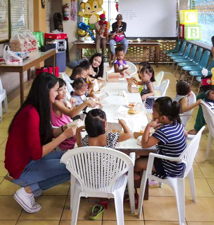 Krystelle and Arabella talk with children as they eat lunch.