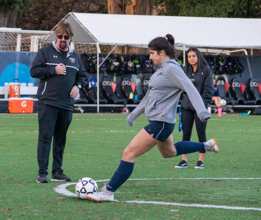 As her coaches watch, Ava Cholakian kicks a ball during practice.
