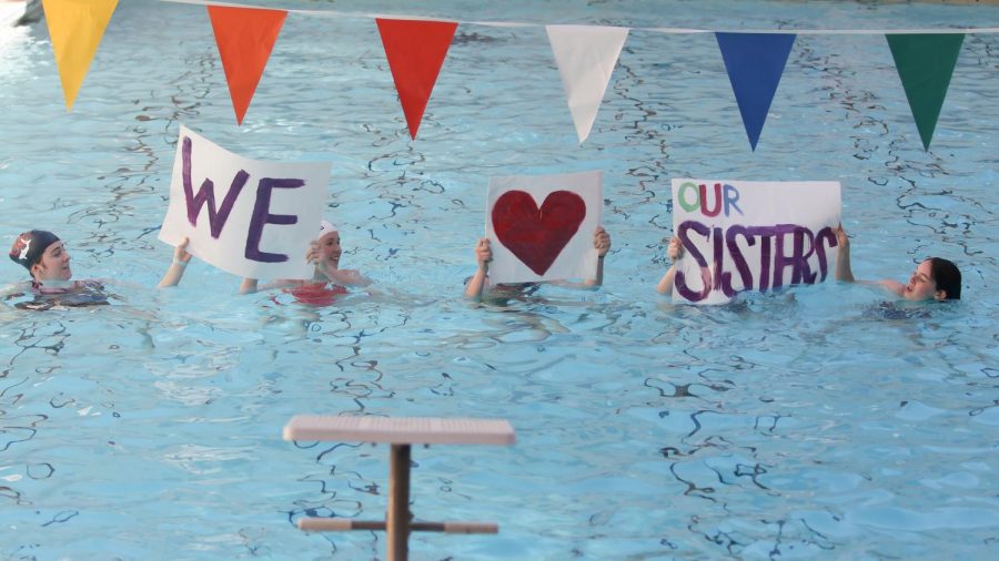 Students perform a group swim routine and hold posters to support sister classes.