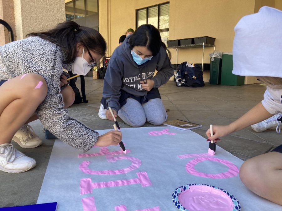 Students spend time after school painting pink breast cancer awareness banners.