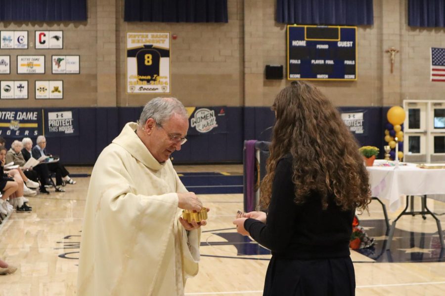 A student receives Communion at the All Saints Day Mass.