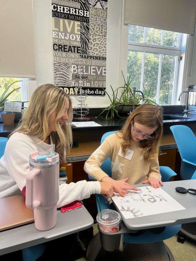 Senior Ashley Strain teaches her 4th-grade sister how to use fingerprinting techniques in forensics class.