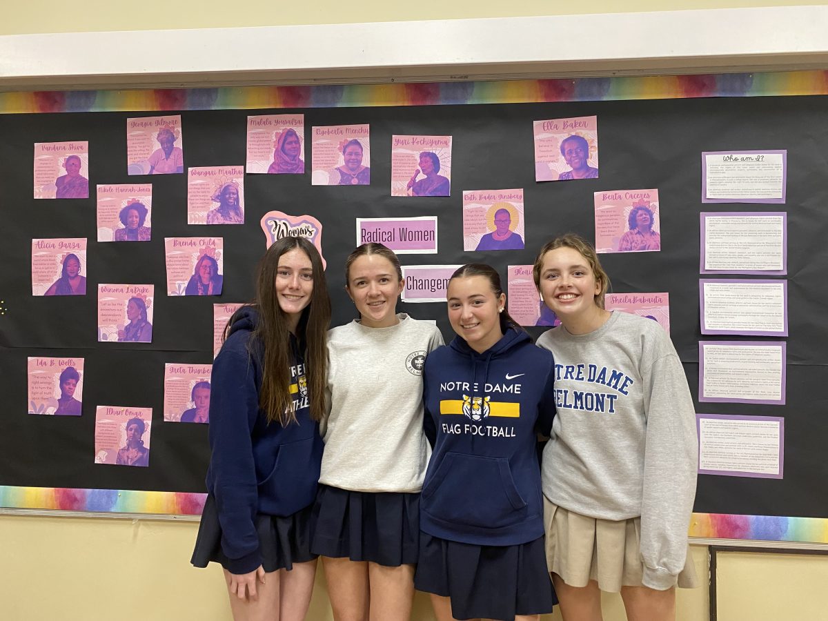Sophomores Sofia Castricone, Olivia McGlynn, Tali Cuneo and Natalie Hurley pose in front of the
March bulletin board, which highlights female accomplishments throughout history.
