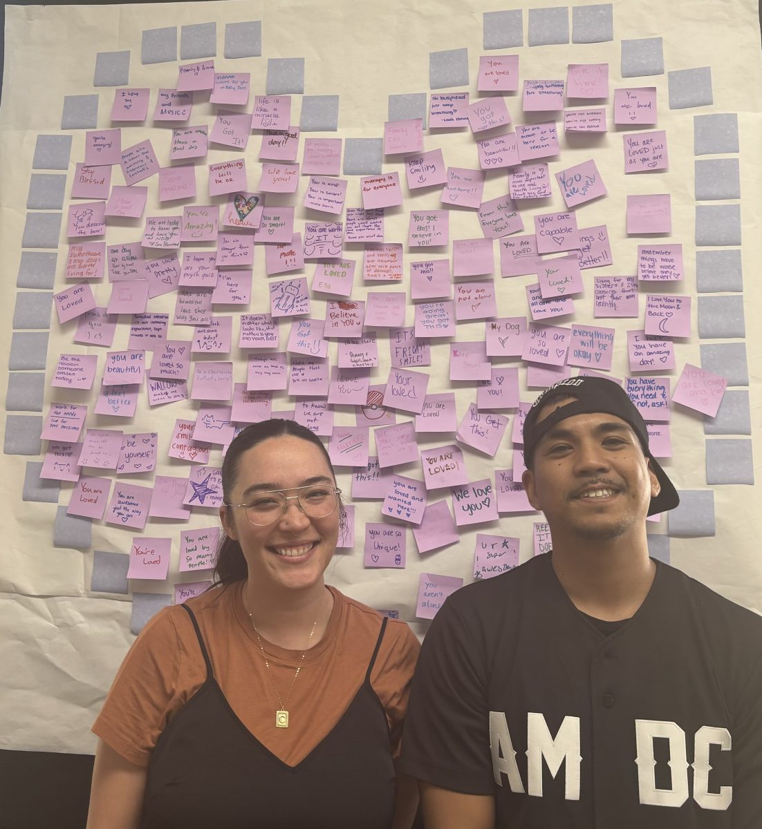 Christina Christenson and Allan Gargaritano pose in front of an affirmation poster for suicide awareness month  