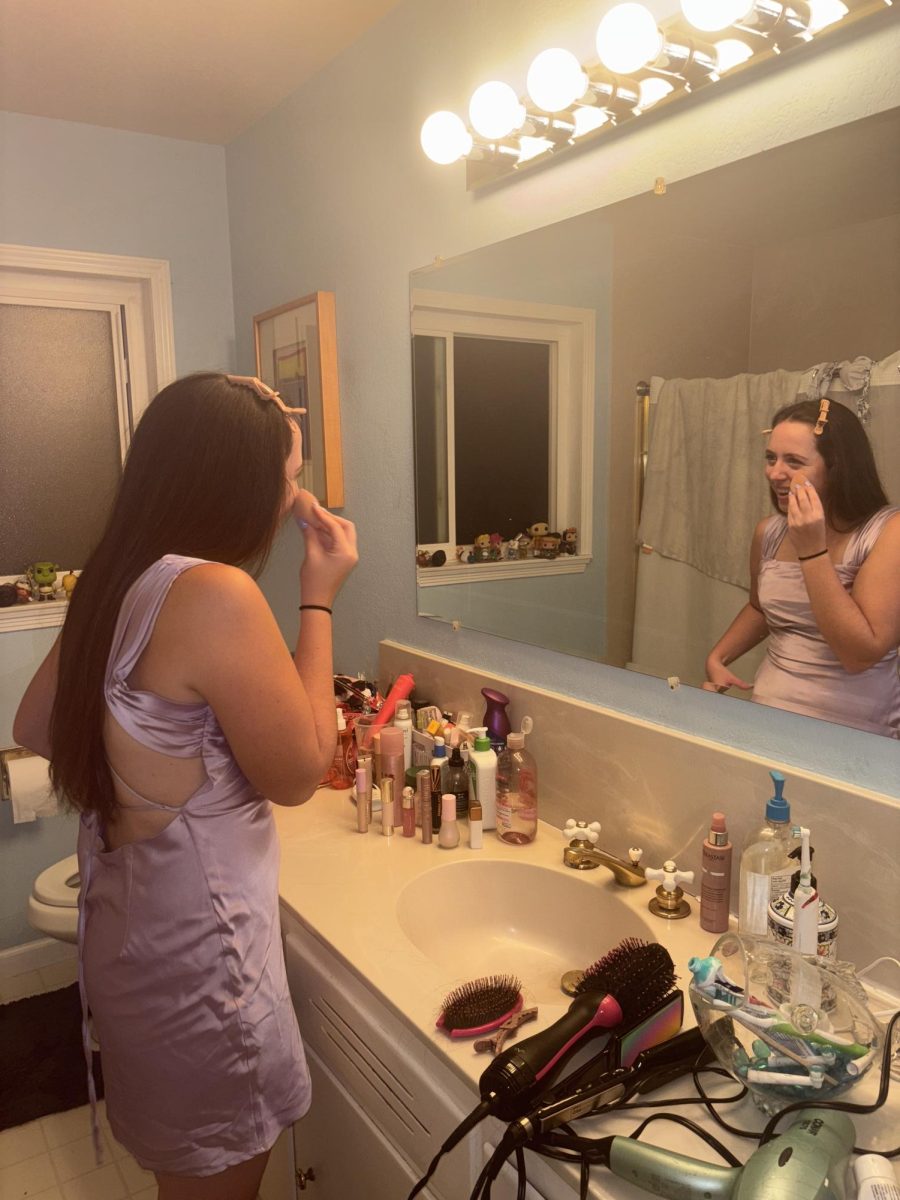 Student is getting ready for the dance by doing their hair and make up.