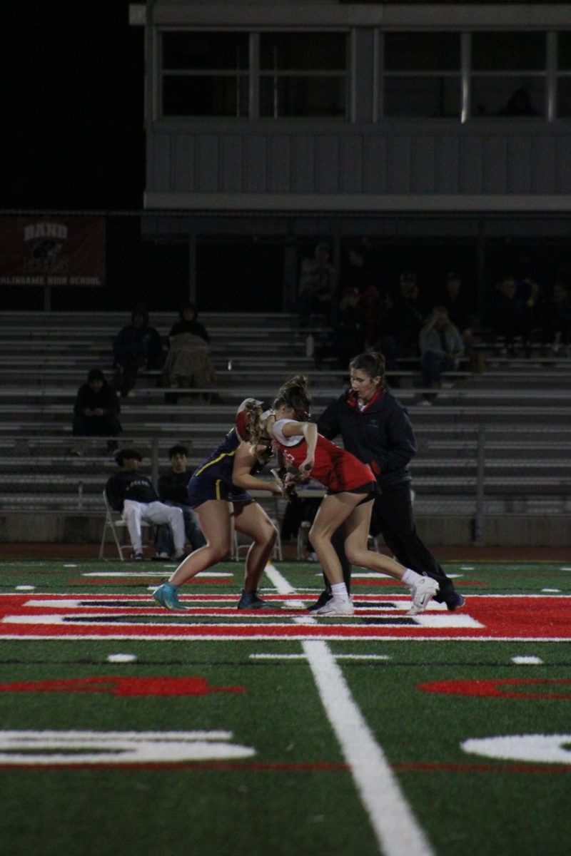 Two varsity lacrosse players take their place on the field as a game is about to kick off.