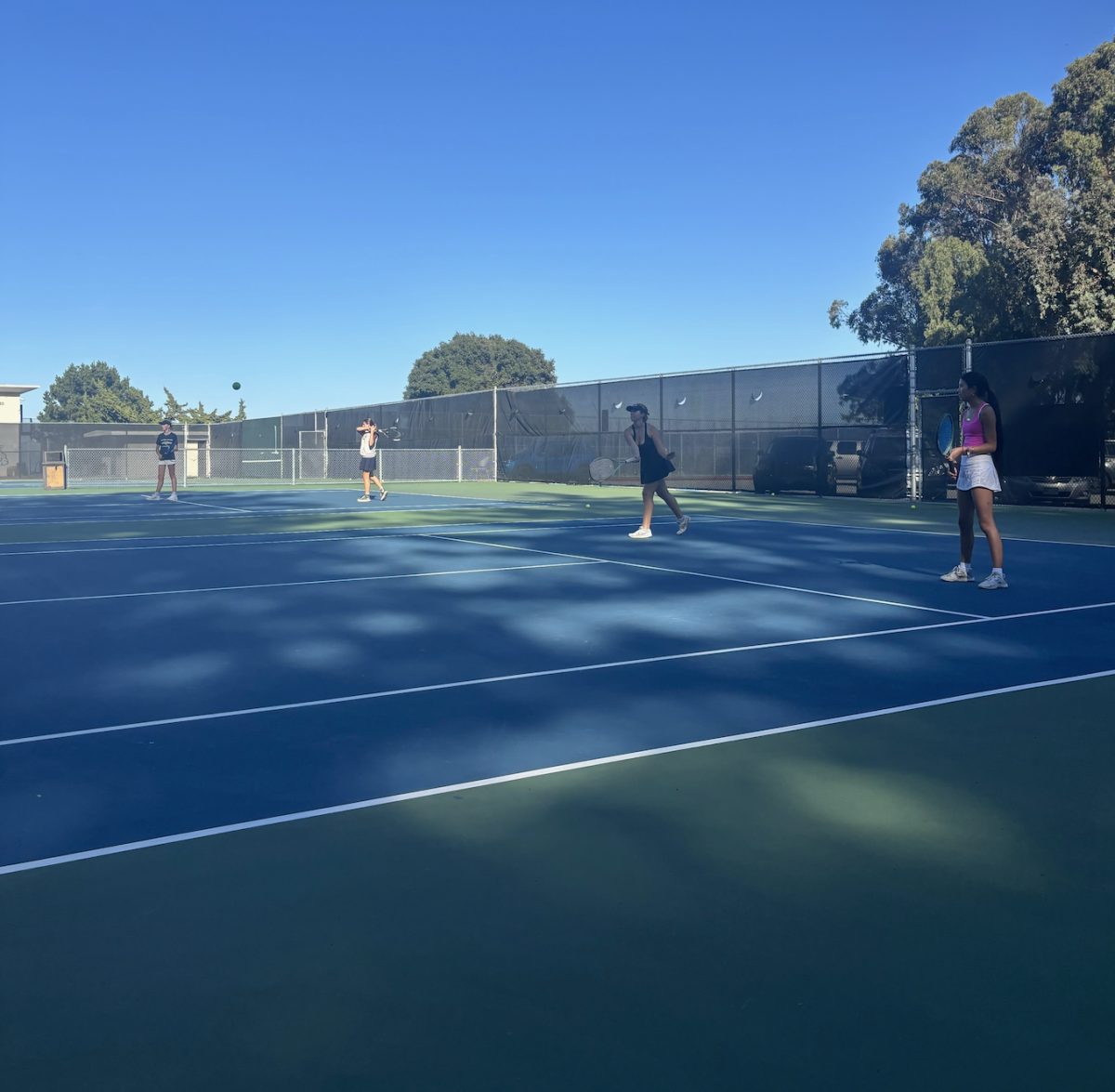 Two tennis players practice their doubles strategies and tactics at a recent practice in preparation for their next match.