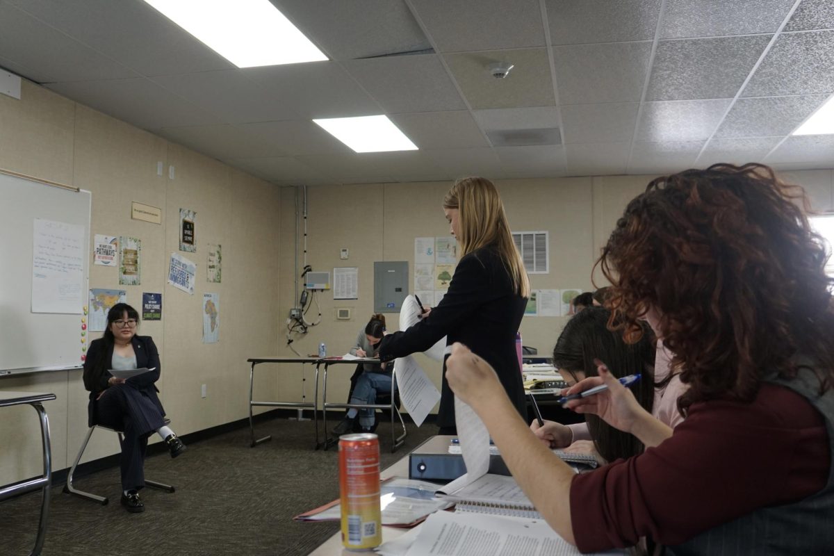 Varsity attorney Elizabeth Scott (center) directs defense witness Elyse Taketa (left).