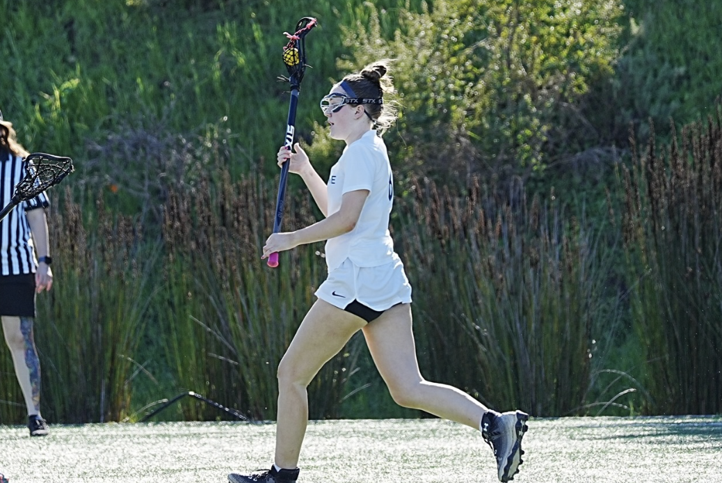 Senior Finley Wilke-Hiland cradles the ball as she runs down field.